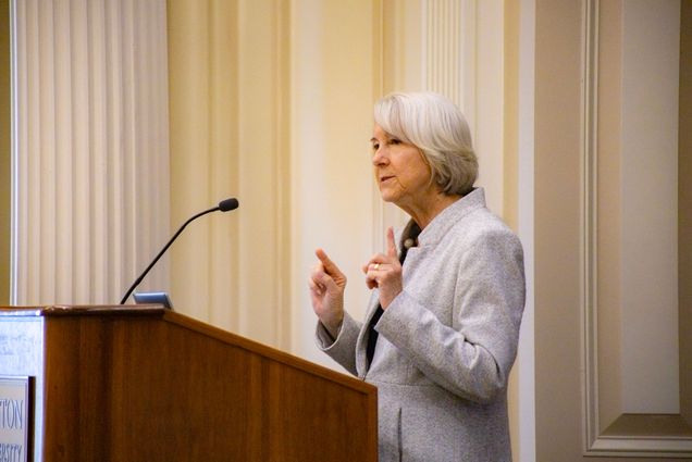 Photo: A woman standing behind a podium and speaking in front of a crowd