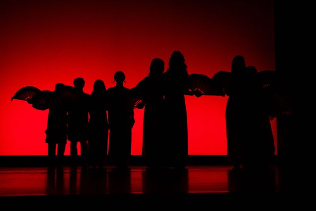 Photo: A red-lit stage with silhouettes dancing