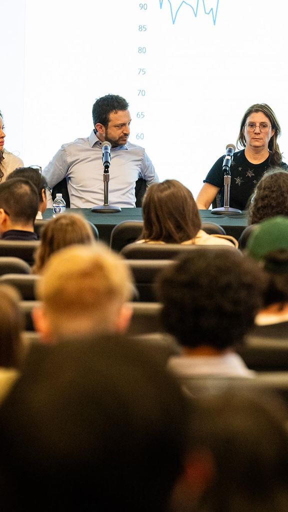 Photo: A panel of five economics speaking to a crowd.
