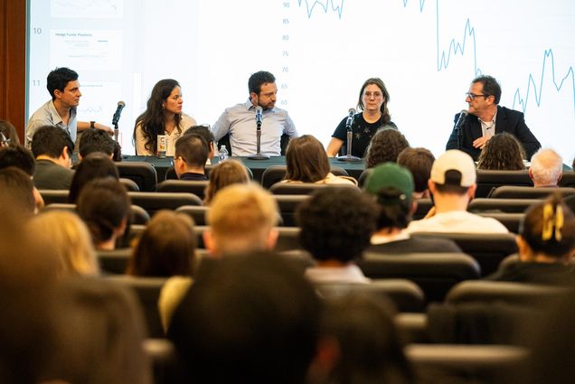 Photo: A panel of five economics speaking to a crowd.