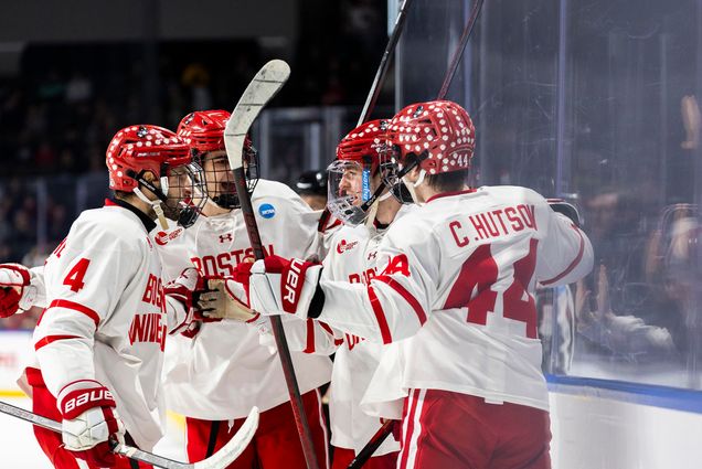 Photo: A group of BU men's hockey huddle and talk on the ice in their uniform.