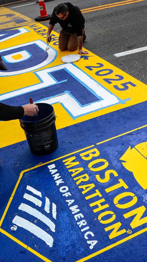 Photo: Workers painting the 2025 Boston Marathon starting line, which features blue and gold coloring