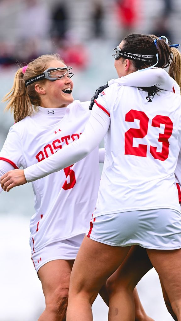 Photo: BU women’s lacrosse players celebrating on the field after winning a game