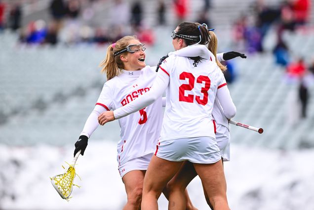 Photo: BU women’s lacrosse players celebrating on the field after winning a game