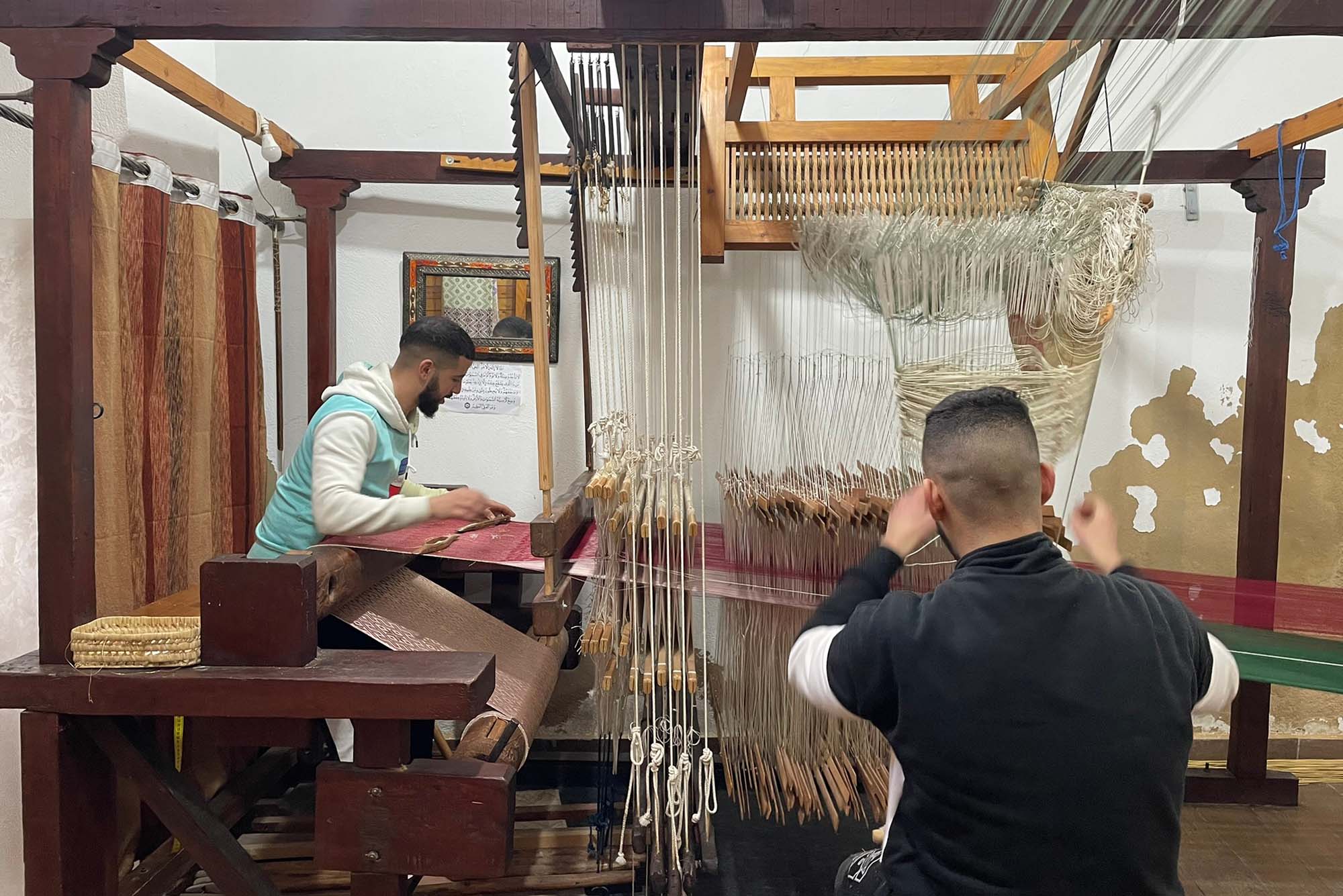 Photo: Two weavers using machines and textiles
