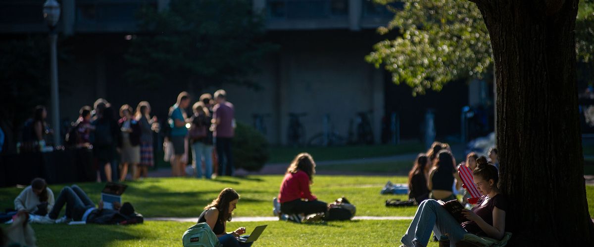 Students seated and standing on lawn outside BU building