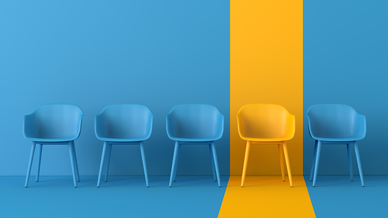 one yellow chair in a row of blue chairs