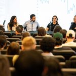 Photo: A panel of five economics speaking to a crowd.