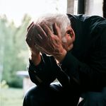 Photo: An older man with white hair and his head in his hands