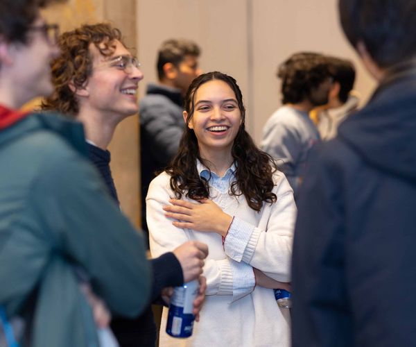 Woman standing and laughing while talking to other students