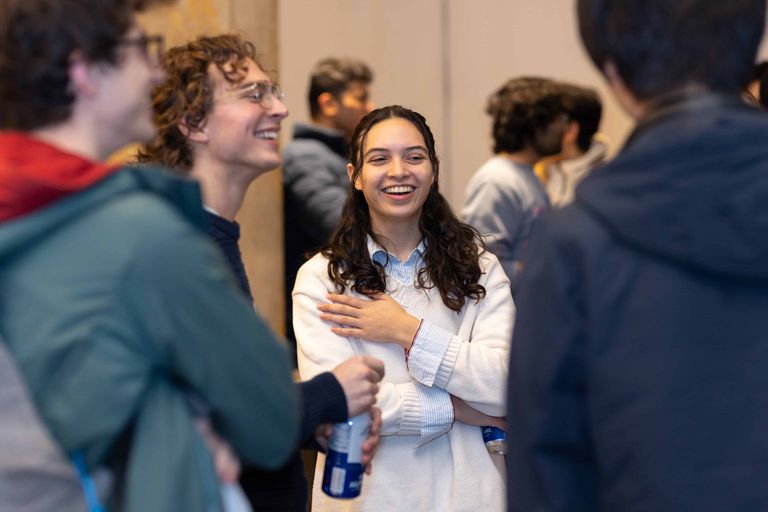 Woman standing and laughing while talking to other students