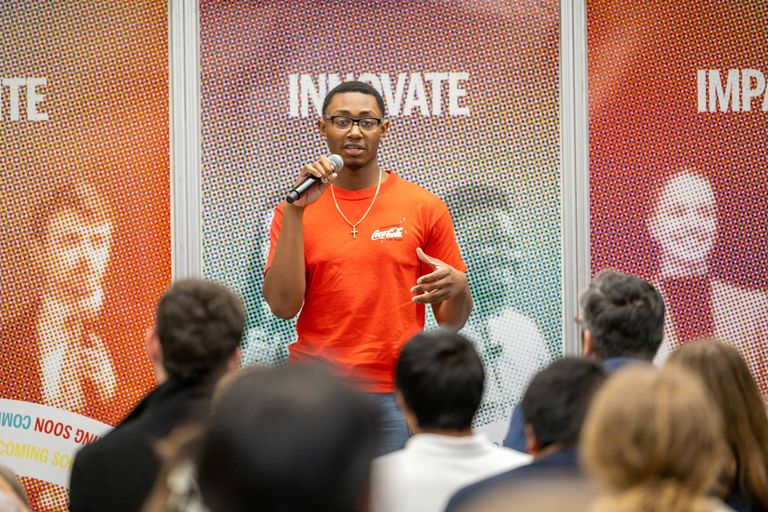 Student presenting in front of a colorful backdrop and holding a microphone