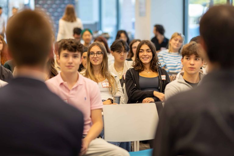 Group of students seated in the audience at an event and smiling