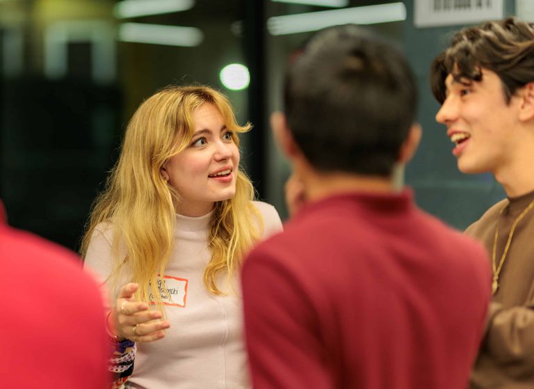 Woman standing engaged in conversation with a group of other students