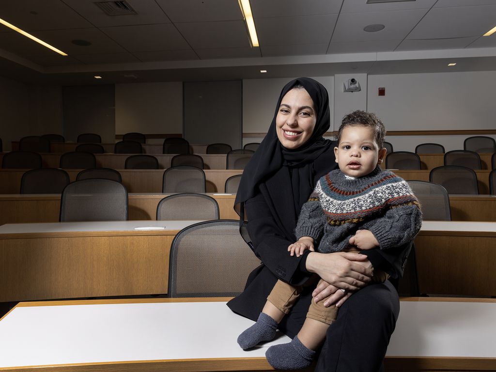 Shaimaa Althubaiti, LLM Class of 2023, sits on a desk in a classroom with her son, Talal