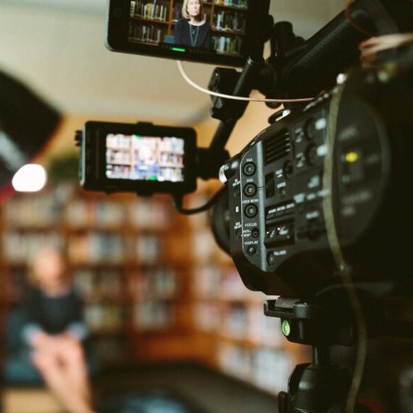 A person sits in a chair in front of a video camera for a media interview