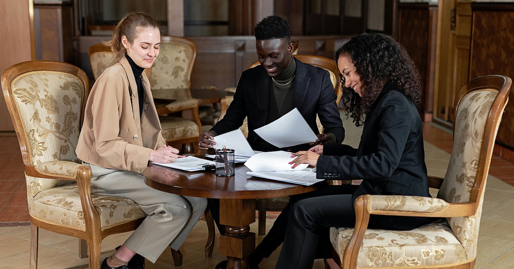 Three law students sit around a coffee table and review paperwork.
