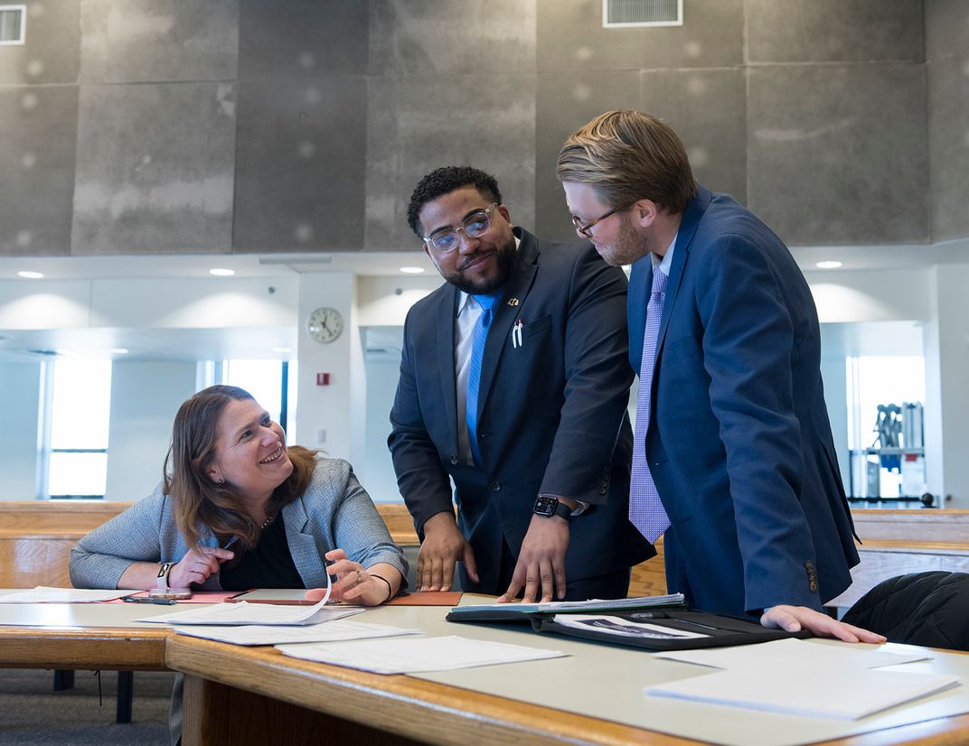 Professor Shira Diner speaks with two students in a courtroom.