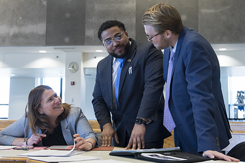 Professor Shira Diner speaks with two students in a courtroom.