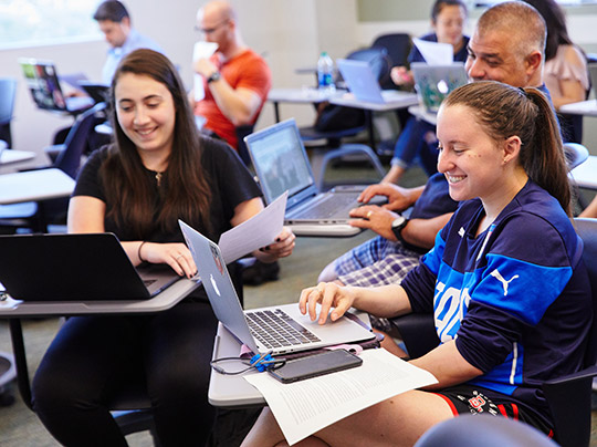 Criminal Justice students working with laptops in a classroom setting at Boston University