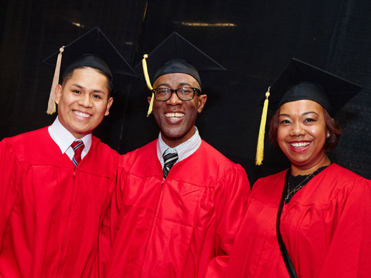 Student Advising - Image shows three students at commencement wearing caps and gowns.