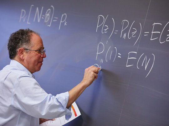 MET Professor Hal Tepfer writing functions on a chalkboard