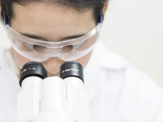 Medical laboratory scientist looking through a microscope