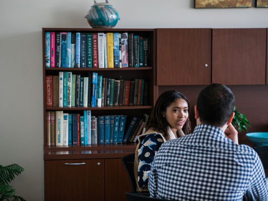 Two students in deep conversation in a library setting discussing Natural Social Sciences.