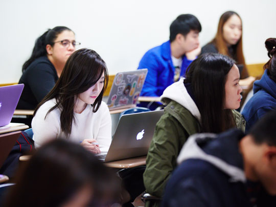 Students at desks working through some course information related to the Risk Management program at BU MET.