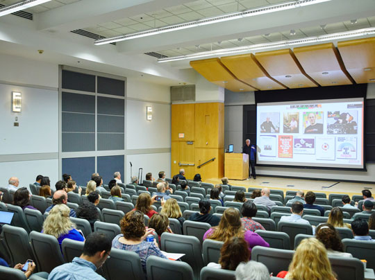 Business students in an auditorium setting watching a presentation on supply chain management.