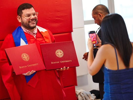 Second Master’s Degree Option is depicted by a student holding up his two degrees at commencement.