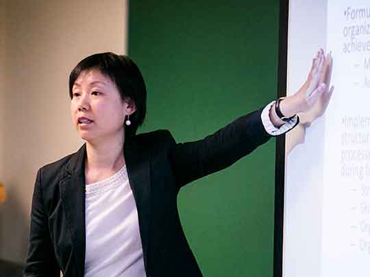 Professor Zhang directs students to a screen with detailed information related to the Health Informatics program at BU MET.