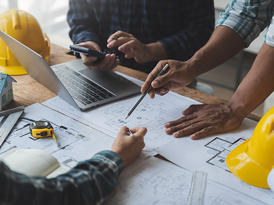 A construction management team reviewing blueprints in an office