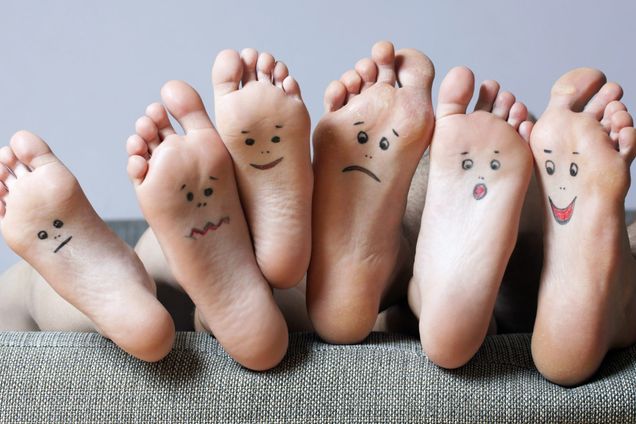 Three sets of feet with smiles drawn on soles