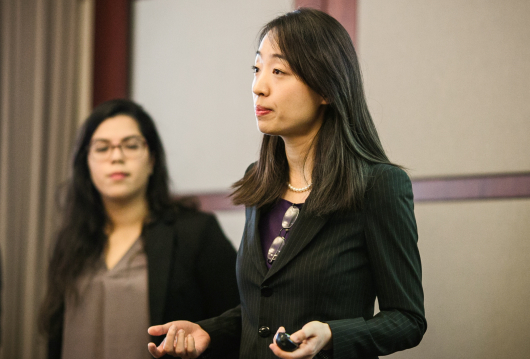 Female professor speaking in front of students as TA looks on