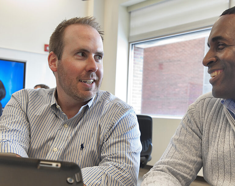 Two men in business attire having a discussion in an office setting