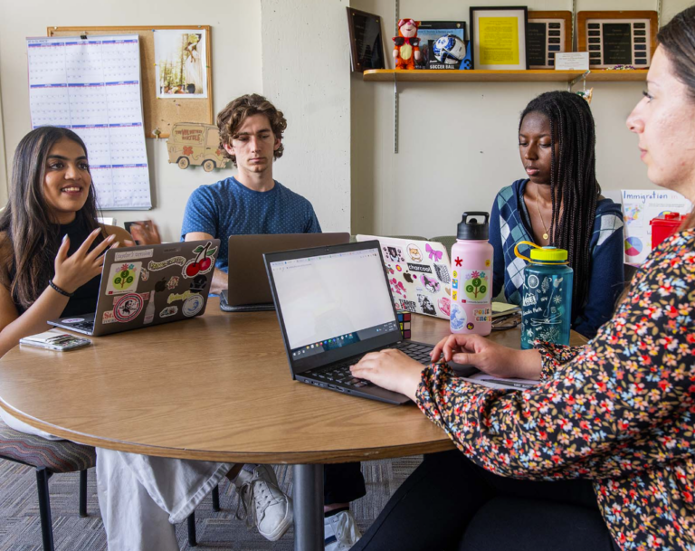 Three students sit around a table with an advisor to plan an event