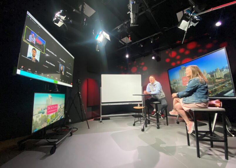 Online MBA lecture studio with professor and guest lecturer facing the screen where students listen in