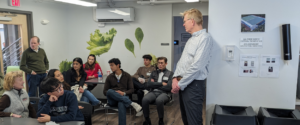 Students listen to the CEO speak at a company visit as part of a course