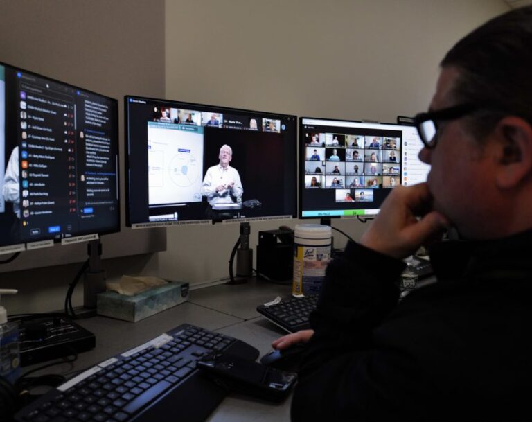Man sits in front of three monitors watching a virtual speaker
