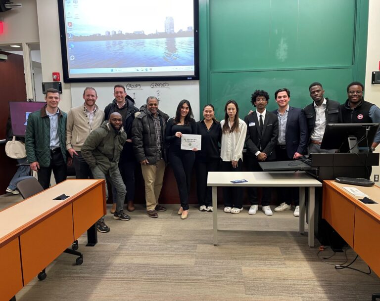Students pose in the front of the classroom, woman student in center holds a certificate