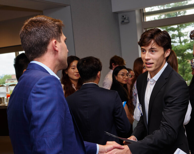 Male student shaking hands with a male recruiter at an employment fair.