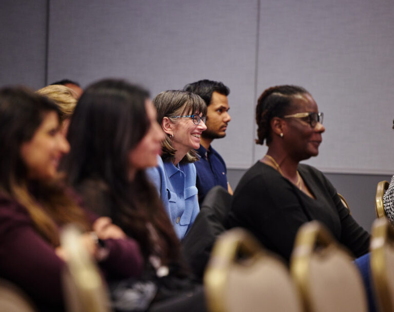 Faculty seated listening to a speaker at an event