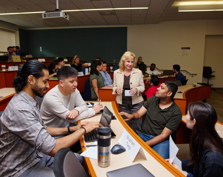 Professor speaking with a group of students in classroom