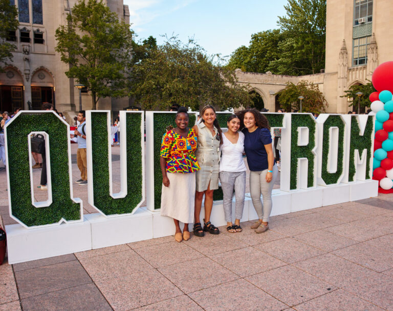 Graduates posing for photo in front of large Questrom signage