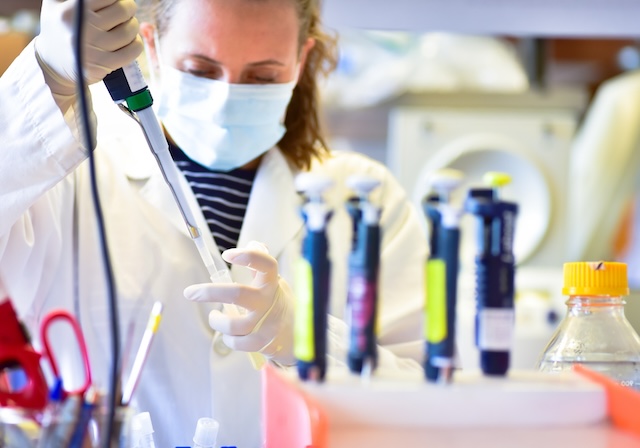 Research at bench in lab working with pipette