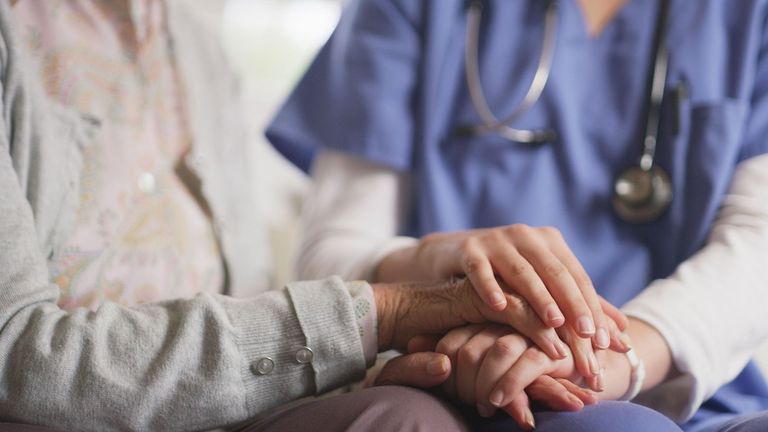 Clasped hands of nurse and elderly patient with Alzheimer's