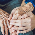 Young woman holding elderly woman's hand
