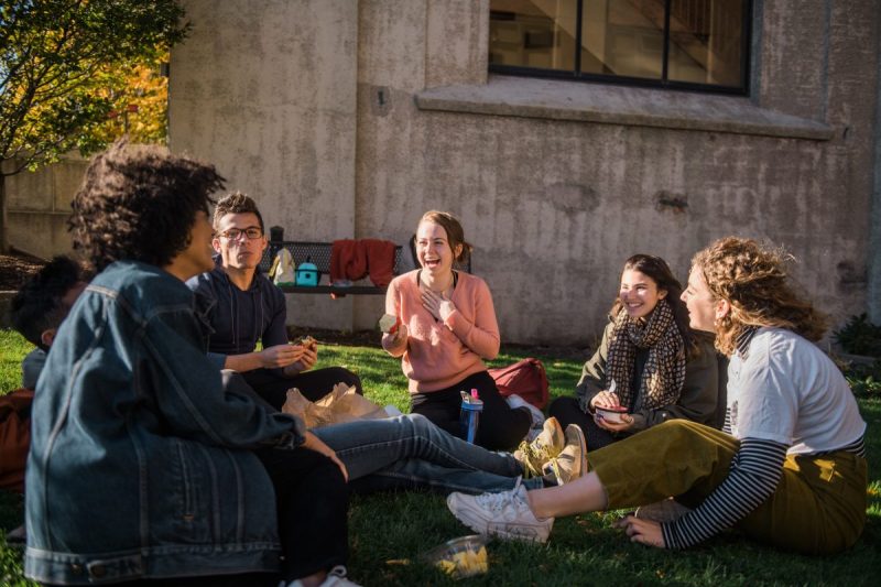 Five students sitting on lawn