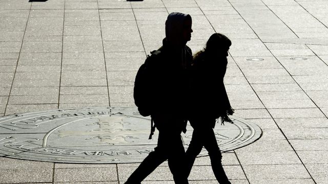 Two students walking outside on campus in shadow